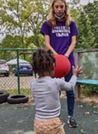 A student volunteer playing with a young boy outside